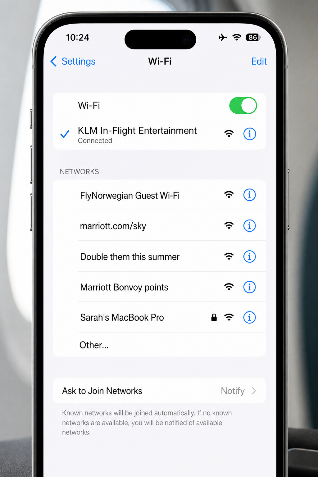Smartphone Wi-Fi list showing an airline network, three SSIDs forming an Airalo eSIM ad, and a passenger's MacBook